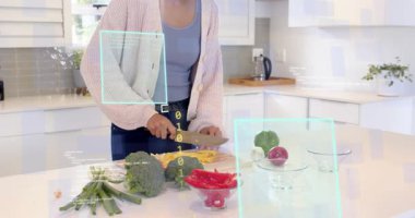 Kadın bıçak seçiyor, adada sarı biber dilimliyor AR 'ı etkinleştiriyor ürünleri analiz ediyor. Yemek pişirme, yemek hazırlama, mutfak, aşçılık, sağlıklı beslenme, modern iç mekan, teknoloji.