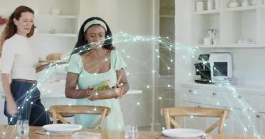 Kadın salata kasesi ile giriş yapıyor. Arkadaşları ekmek düzenleme masasını yerleştirirken. Aşçılık, işbirliği, aşçılık, konukseverlik, modern, dostane, uyum