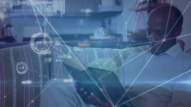 Son sınıf öğrencisi kitapla dinlenme odasına yerleşiyor, okurken teknoloji ağı kaplamasını başlatıyor. Emeklilik, rahatlık, rahatlık, bağlantı, rahatlama, modern, ev