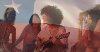 Gitarist gitarı kaldırırken ve bayrak altında çalarken alkışlayan arkadaşlar müziği paylaşıyor. Kutlama, yoldaşlık, açık hava, eğlence, melodi, sükunet, yaşam tarzı.