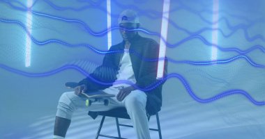 Stüdyodaki taburede oturan kaykaycı neon tüpleri ve mavi dalga izleri vardı. Kentsel, modern, neon, fütürist, dinamik, çok yönlülük, gençlik