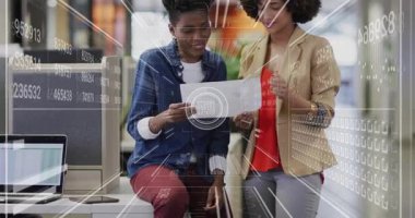 Ofis arkadaşları basılı grafiği işaret ediyor ve eğilimleri analiz ederken animasyon örtülerini aktifleştiriyor. İş, takım çalışması, veri, analitik, profesyonel, işbirliği, teknoloji