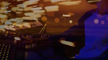 Erkek ses mühendisinin konsol düğmelerine ulaşması, camların arkasında turuncu kıvılcımları dengeleyen müzik karışımına neden oluyor. Müzik, ses, kayıt, stüdyo, yapım, teknoloji, performans