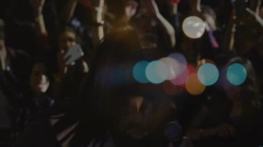 Şarkıcı sahneye adımını atar ve mikrofona şarkı söylemeye başlar. Performans, konser, ışıklandırma, kalabalık, eğlence, sahne, enerji