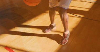 Basketbolcu bacaklarının arasına top sürüyor ve antrenman için sahada antrenmana devam ediyor. Sporcu, spor, antrenman, dinamik, açık hava, odaklanma, hareket