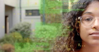 Temiz çerçeveli gözlüklü ve halka küpeli bir genç avluda kod analizi yapıyor, kopyalama alanı. Teknoloji, yenilik, gençlik, eğitim, dijital, modern, yaratıcılık