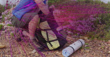 Çömelmiş yürüyüşçü sırt çantalarını kayalık patikada sarı paket, ped ve botlarla emniyet altına alıyor. Kopya alanı. Macera, keşif, vahşi doğa, açık hava, engebeli, hayatta kalma, doğa