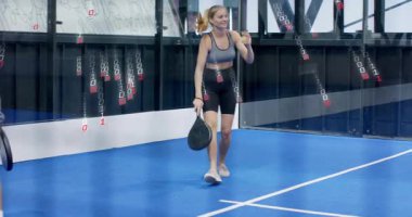 Dişi Padel oyuncusu sarı topu alıyor ve maç antrenmanı için forehand vuruşlarına başlıyor. Atletik, spor, antrenman, rekabet, canlı, dinamik, takım çalışması