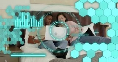 Kadın ve erkek yatağın üzerine dizüstü bilgisayar açısını ayarlıyor, rahat teknolojik tarama için ekranı daktilo ediyor ve işaret ediyor. Günlük, samimiyet, rahatlama, teknoloji, ev, iletişim, yaşam tarzı