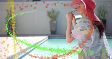 Güneş gözlüğü kaldıran ve havuz kenarında kayan bir kadın, etrafını süpüren pazarlama parçacıkları. Rıhtım, güverte, açık hava, tatil, şık, canlı, pastel