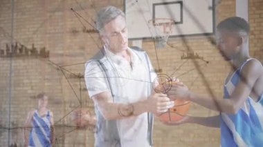 Koç, tutuş eğitimini gösteren düğümlerle sahada öğrencinin basketbol tutuşuna uzanıyor ve rehberlik ediyor. Akıl hocası, spor salonu, teknik, el pozisyonu, top, odaklanma, dinamik