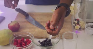 Sağlıklı meyve suyu hazırlamak için böğürtlenleri kabın içine karıştıran bir adam. Sağlıklı beslenme, smoothie, beslenme, mutfak, yaşam tarzı, tazelik, sağlık