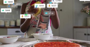 Mutfakta peynir rendeleyen bir kız, sosyal medya pazarlamasını canlanmış parmaklar ve kalplerle ateşleyen bir kız. Gıda hazırlama, yemek pişirme, yerli sahne, sosyal medya, dijital bağlantı, yaşam tarzı, canlı