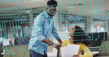 Oturan kadına doğru yürüyen bir adam, iş belgelerini masasının üzerinde kaybolan Cyan örtüsü olarak gözden geçiriyor. İşbirliği, iş arkadaşları, ofis, takım çalışması, kağıtlar, monitörler, çalışma alanı