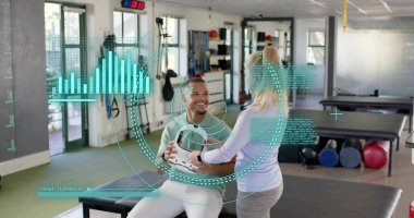 Yeşil tişörtlü, elinde tıp topu, gri taytlı terapist rehabilitasyondaki hareketlere rehberlik ediyor. Terapi, antrenör, klinik, hareketlilik, güç, ekipman, gün ışığı