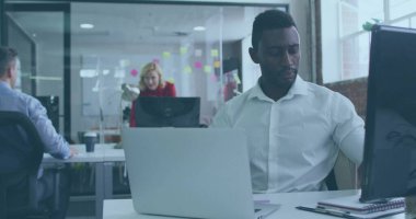 Çalışan adam dizüstü bilgisayarda yazı yazıyor ve açık planlı ofiste yapışkan notlarla izliyor. İşbirliği, takım çalışması, modern, profesyonel, çalışma alanı, yenilik, üretkenlik