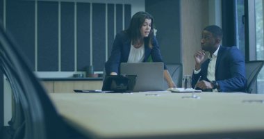 Resmi giyinmiş profesyoneller toplantı odasında dizüstü bilgisayar, telefon ve kağıtlarla fikirleri tartışıyorlar. Şirket, işbirliği, takım çalışması, modern, profesyonel, iş dünyası, tartışma