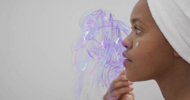 Beyaz havluya sarılı kremalı kadın aynanın karşısında yanardöner girdaplarla duruyor, kopyalama alanı. Cilt bakımı, güzellik, özbakım, sağlık, yansıma, kaplıca, lüks.