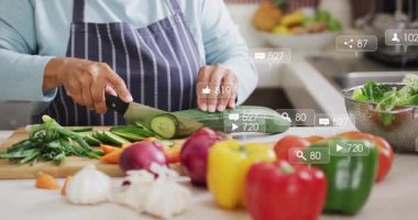 Salatalık yerleştirmek, kıdemli aşçı yüzen sosyal medya ölçümleriyle sebzeleri doğramak. Aşçılık, aşçılık, sağlıklı beslenme, mutfak gereçleri, sosyal medya, nişan, tazelik