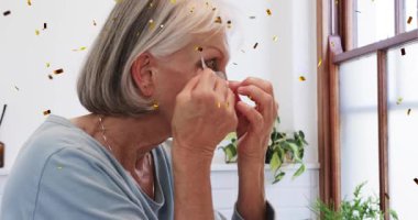 Cilt bakımını başlatan yaşlı kadın gri jel bandı seçerek ve göz altı bakımı uygulayarak rutin hale geliyor. Yaşlanma karşıtı, sağlık, güzellik, rahatlama, kendine bakım, yaşam tarzı, minimalizm