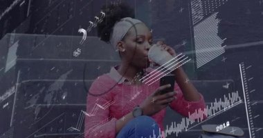 Bir kadın oturmuş bardak kaydırmalı telefonu yudumluyor ve çerçevede hareketli finans tablolarına neden oluyor. Akıllı telefon, kupa, sırt çantası, kaykay, açık hava, şehir, süveter