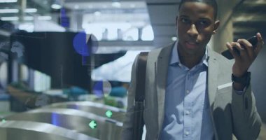 Turnikeler aracılığıyla göreve gelen bir adam, etrafında dijital örtüler beliriyor. Profesyonel, yönetici, gri, takım, mavi, gömlek, deri