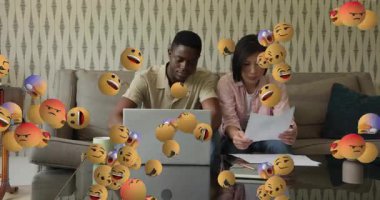 Dizüstü bilgisayarda yazan ve kağıtları sıralayan bir çift, sosyal medya değerlendirmesi sırasında emoji geribildirimi yaratıyor. İşbirliği, takım çalışması, iletişim, dijital, gündelik, modern, etkileşim