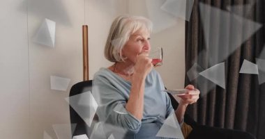 Ekranda sürüklenen üçgen örtüler, yaşlı bir kadının sağIık için cam çay fincanını kaldırmasına rehberlik ediyor. Rahatlama, farkındalık, dinginlik, iç mekan, minimalizm, tefekkür, konfor