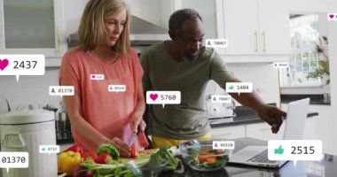 Kadın mutfakta salata hazırlarken, erkek dizüstü bilgisayarda animasyon pazarlama ölçülerinin değiştiğini görüyor. Aşçılık, sosyal medya, katılım, işbirliği, modern, canlı, yaşam tarzı