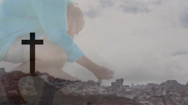 Kıdemli adam uzanıp elini uzatıyor, film için haç ve kayalarla çözerken sunuyor. Siluet, açık hava, anıt, manzara, düşünceli, saygılı, katmanlı.