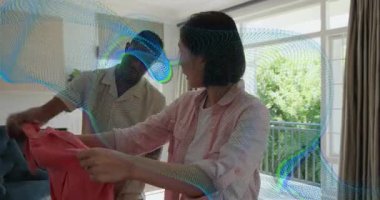 Kırmızı gömleği kaldıran kadın, çift ev dekorunda kollarını hizalarken hareketli katlama rehberini tetikliyor. Romantik, samimiyet, ev, yaşam tarzı, rahat, uyum, bağlantı