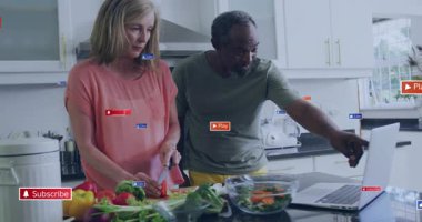 Kadın ve erkeğin yemek pişirme dersi için dizüstü bilgisayara kayan sebze dilimleme işlemini başlat. Aşçılık, aşçılık, takım çalışması, tazelik, modern, yerli, öğretim