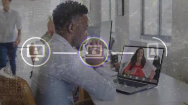 Masada iş görüşmesine katılan bir adam, sunucu konuşması, bağlantı simgeleri ve dizüstü bilgisayarın üzerinde noktalı örtüye neden oluyor. Uzaktan kumanda, toplantı, ofis, işbirliği, takım çalışması, gün ışığı, teknoloji