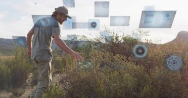Beyzbol şapkası takan adam çöldeki dijital panellerle çalılıklara uzanıyor. Teknoloji, yenilik, keşif, belgesel, fütüristik, profesyonel, çevresel