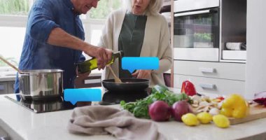 Mutfak sebzelerini karıştıran kadın yemek hazırlarken kıdemli adam tavaya zeytinyağı döküyor. Çift, yemek, mutfak, mutfak gereçleri, ev, sağlıklı, yaşam tarzı