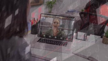 Uzaktan hoparlör konuşuyor ve meslektaşı toplantıyı izlerken dizüstü bilgisayardan animasyon çizelgeleri başlatılıyor. Video konferansı, iş arkadaşları, işbirliği, çalışma alanı, masa, bilgi grafikleri, bitki