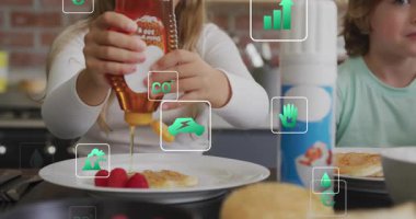 Kardeşler, kahvaltıyı tatlandırmak için kreplere bal döküyorlar. Çevrelerinde kıvılcımlar saçıyorlar. Aile, kahvaltı, mutfak, sürdürülebilirlik, doğal, sağlıklı, yaşam tarzı