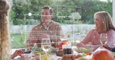 Merkezdeki adam el kol hareketi yaparken verileri açıklıyor, AR teknolojisi panelleri masanın etrafında büyüyor. Açık hava, yemek, bahçe, aile, arkadaşlar, üst üste, canlı