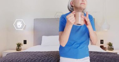 Üst düzey kadın yatak odasına giriyor ve canlandırılmış ekolojik ikonlar enerji kullanımını görselleştirirken yatakta oturuyor. Eski, rahat, rahatlatıcı, çevresel, sağlıklı, modern, sakin