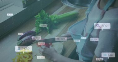 Ev aşçısı kırmızı biber doğruyor. Mutfakta sosyal medya takipçilerinin büyüdüğünü gösteren rozetler yakıyor. Aşçılık, mutfak, aşçılık, yemek, yemek hazırlama, iç mekan, yaşam tarzı