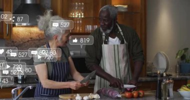 Kıdemli kadın ve erkek yiyecek doğrama sosyal medya pazarlama ikonlarının büyümeyi izlemesine neden oluyor. Aşçılık, işbirliği, ev, yaşam tarzı, çağdaş, dijital, etkileşim