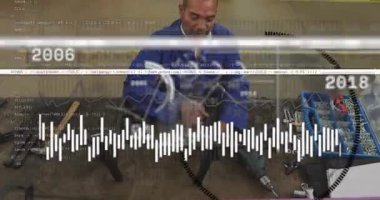 Teknik ekip yedek kulübesinde parçaları birleştiriyor, zaman çizgisi grafikleri ortaya çıkıyor ve tarihi gösteriyor, gülümsemeye neden oluyor. Atölye, teknisyen, metal işçiliği, makine, sanayi, adanmışlık, veri