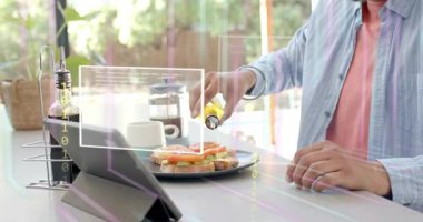 Adam mutfak masasında oturmuş cam kenarına yağ serpiştiriyor, sandviç kaplıyor ve AR-HUD ikili sistem teknolojisine sebep oluyor. Kahvaltı, artırılmış, üst üste, tablet, baharat, güneş ışığı, ev