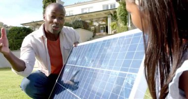 Adam diz çöküp çimlere güneş teknolojisi öğretiyor, çocuk panele dokunuyor, matematik örtüsü oluşuyor. Fotovoltaik, eğitim, gösteri, çocuk, enerji, geometri, açık hava