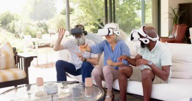 Kanepedeki bir grup arkadaş sanal gerçeklik teknisyeniyle iletişim kurarken yüzen arayüze uzanıp işaret ediyorlar. Sanal, gerçeklik, jestler, işbirliği, sosyal, günışığı, kulaklık