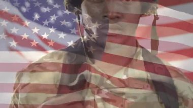 Asker kayışı ayarlıyor, kamera kendini belli ediyor, bayrak sallanıyor, orduyu onurlandırıyor. Kask, kamuflaj, üniforma, gözlükler, teçhizat, kampanya, stoik