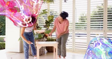 Anne ve kızı DIY için yuvarlanan boya masasını işaret ediyor. Pembe mavi girdaplar onları kısmen gizliyor. Takım çalışması, güneş odası, gün ışığı, ev yapımı, dekor, mobilya, fabrikalar