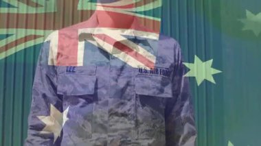 Havacı başını eğiyor, kolunu kaldırıyor ve Avustralya bayrağının hizalı gövdesini onurlandırmak için selam veriyor. Ordu, üniforma, yamalar, şapka, hangar, dış, gün ışığı.