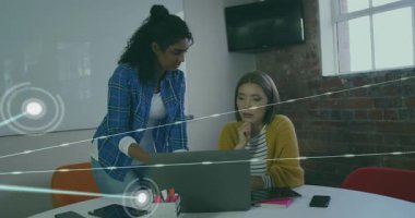 İş görüşmesinde dizüstü bilgisayara yaslanan iki kadın veri gösteren bir ağ oluşturuyorlar. İşbirliği, takım çalışması, yuvarlak masa, ofis, konferans, beyaz tahta, görselleştirme