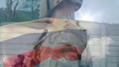 İki asker askeri yerleşkede nöbet tutuyor, bayrak yüzler ve tüfekler arasında dalgalanıyor. Kamuflaj, miğfer, silahlar, bariyer, bulutlar, yoldaşlar, çevre